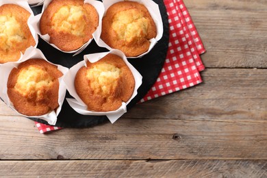 Photo of Delicious sweet muffins on wooden table, top view. Space for text