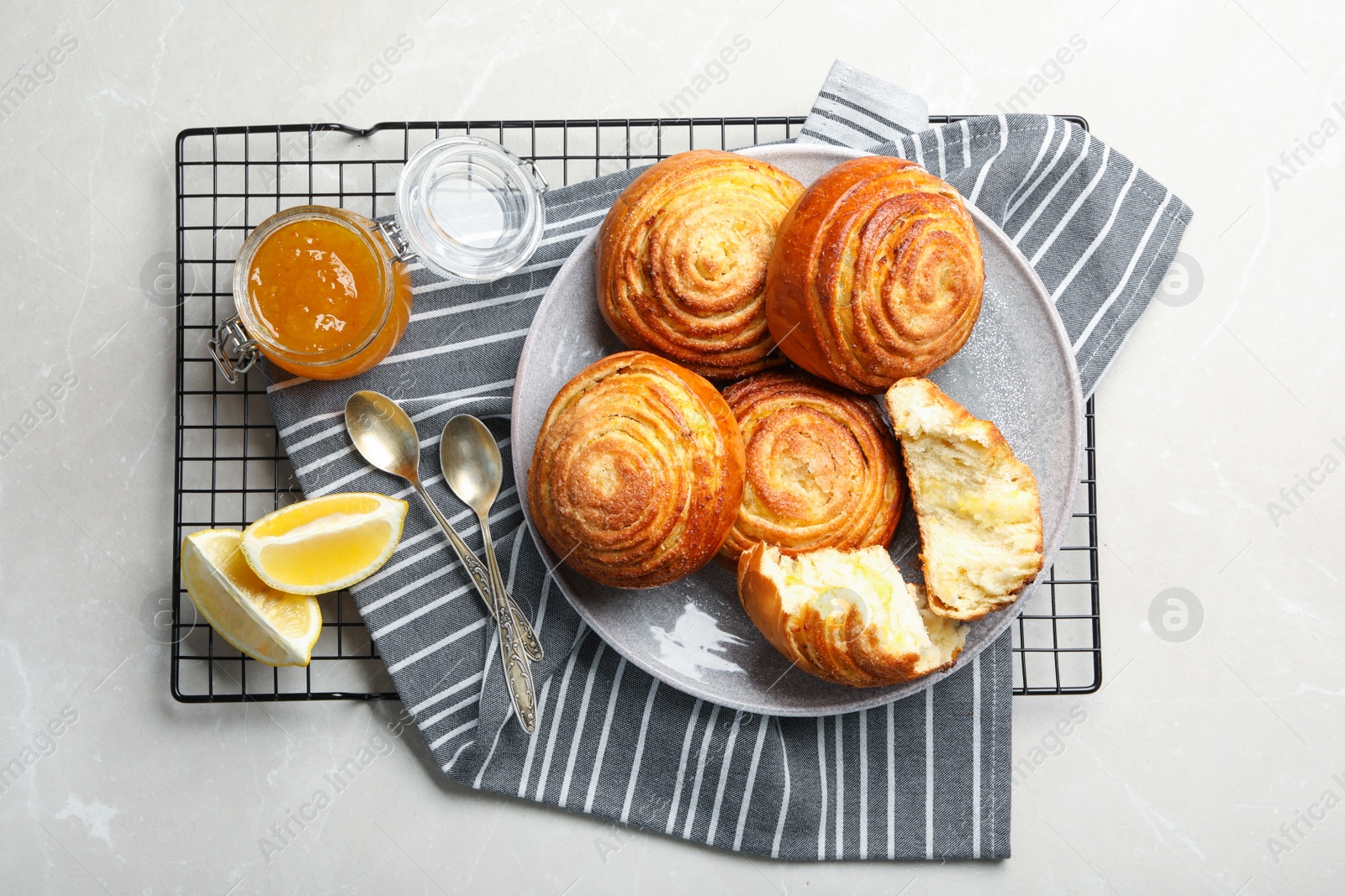 Photo of Flat lay composition with buns, lemon slices and jam on light stone background. Fresh from oven