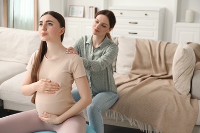 Doula massaging pregnant woman at home. Preparation for child birth