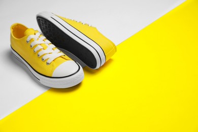 Pair of yellow classic old school sneakers on color background, space for text