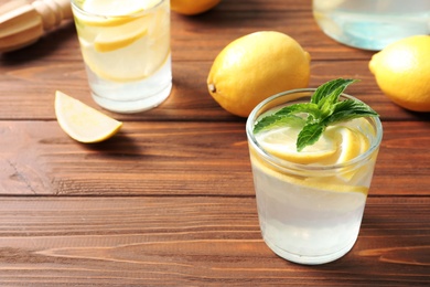 Photo of Natural lemonade with mint in glass on wooden table