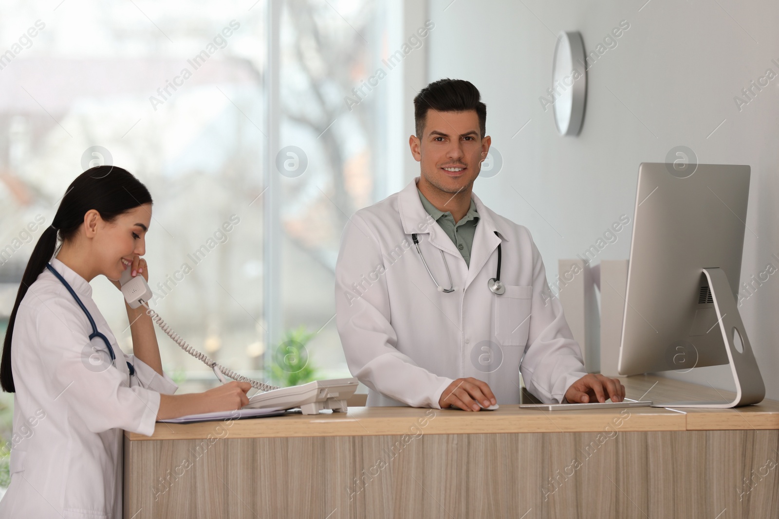 Photo of Receptionist and doctor working at countertop in hospital