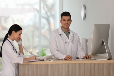 Photo of Receptionist and doctor working at countertop in hospital