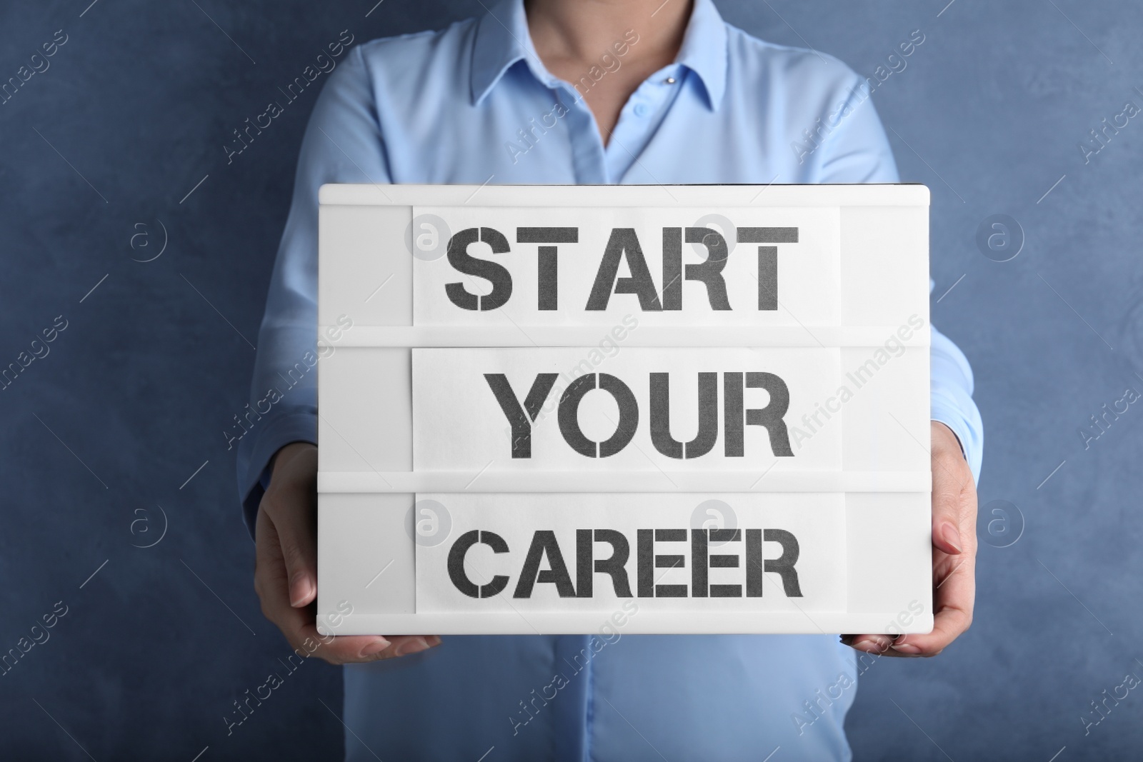 Photo of Woman holding board with words START YOUR CAREER on blue background, closeup
