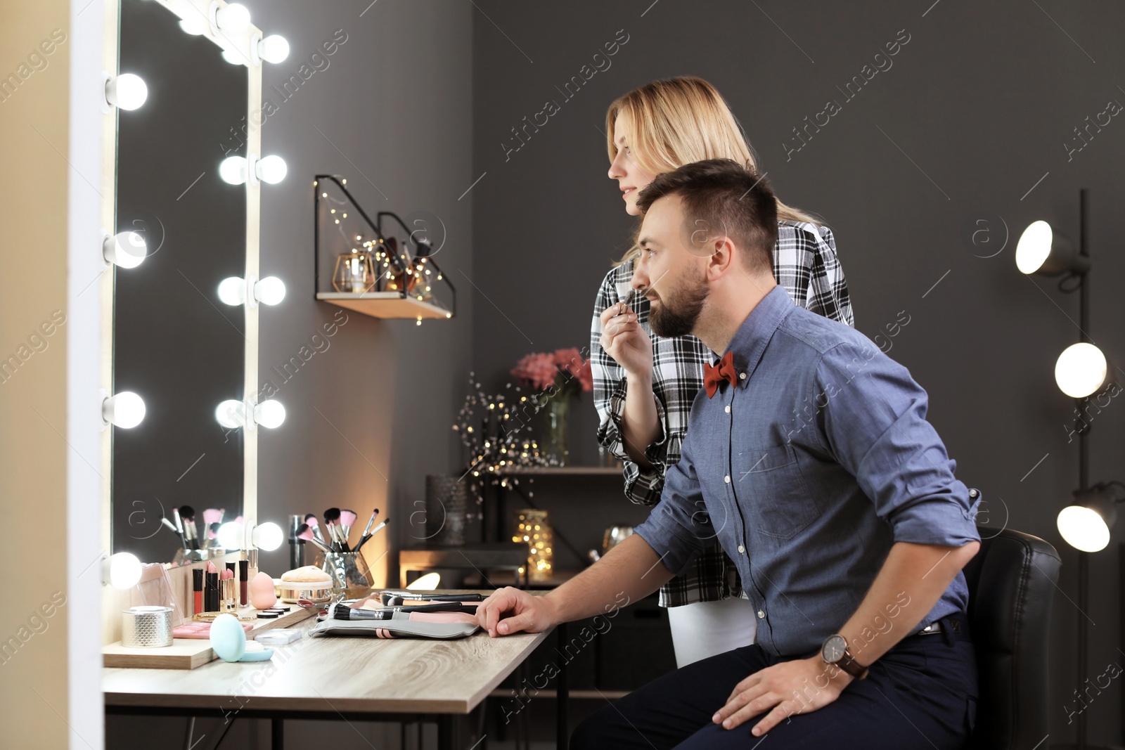 Photo of Professional makeup artist working with client in dressing room