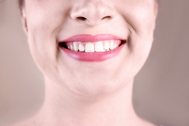 Young woman with healthy teeth smiling on color background, closeup