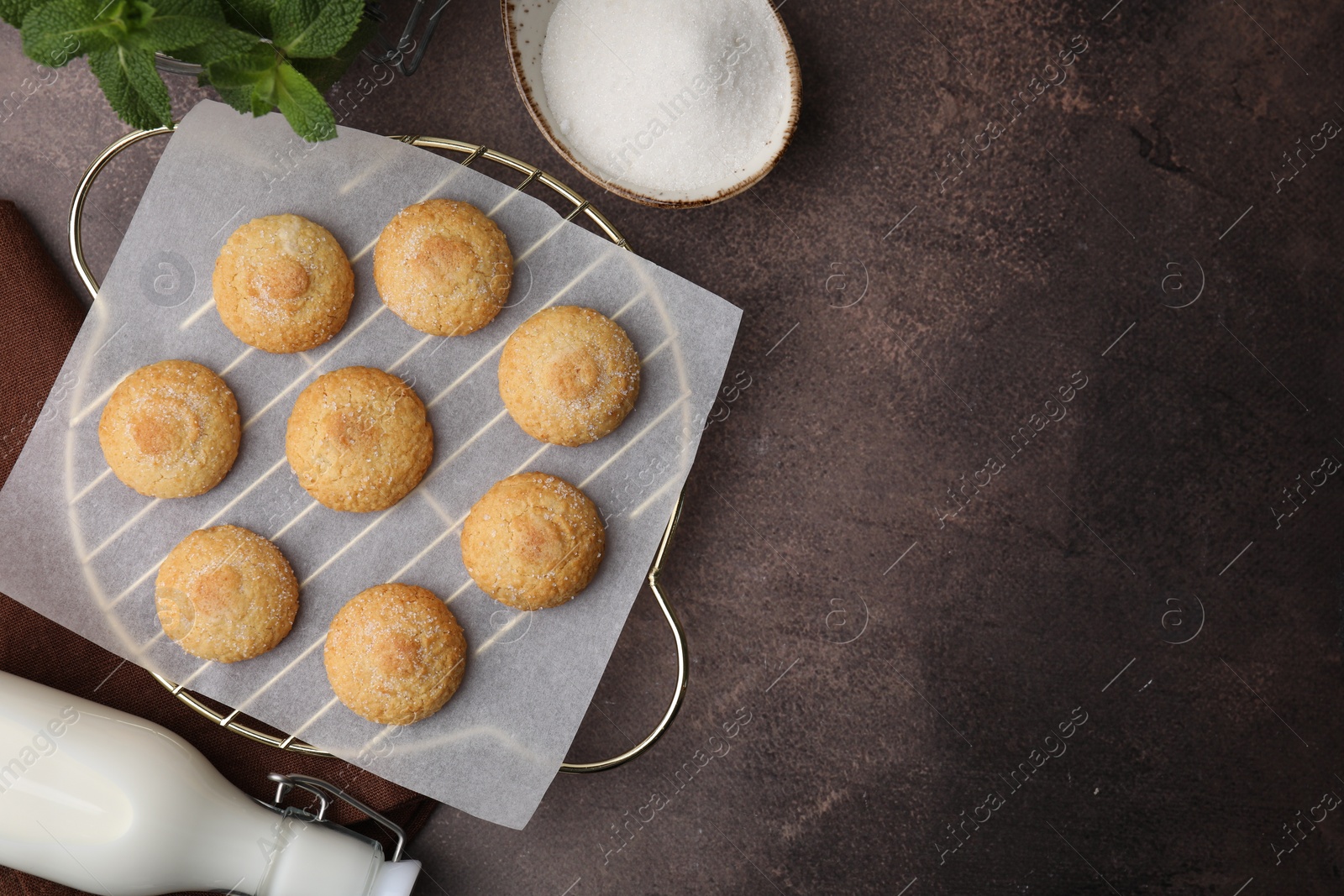 Photo of Tasty sweet sugar cookies, milk and mint on brown table, flat lay. Space for text