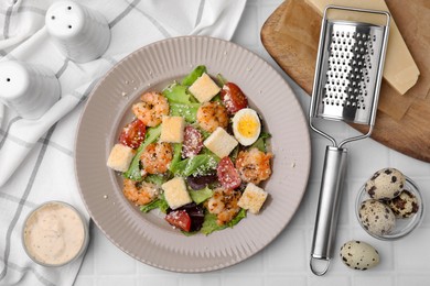 Delicious Caesar salad with shrimps and ingredients on white tiled table, flat lay