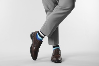 Photo of Man in stylish colorful socks, shoes and pants on white background, closeup