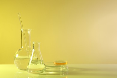 Photo of Laboratory analysis. Different glassware on table against yellow background, space for text