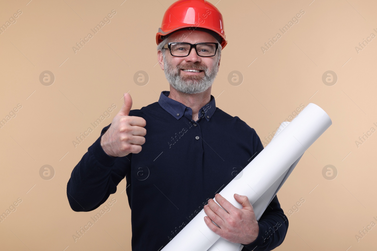 Photo of Architect in hard hat holding drafts and showing thumb up on beige background