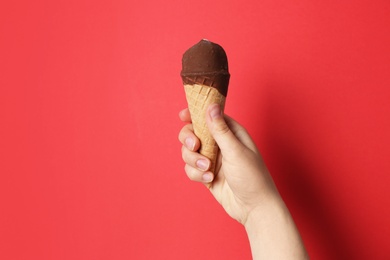 Photo of Woman holding ice cream in waffle cone against color background