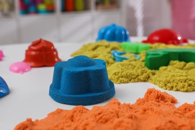 Bright kinetic sand and toys on white table indoors