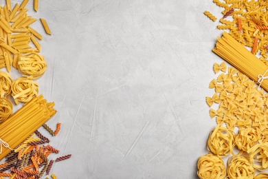 Photo of Flat lay composition with different uncooked pasta on grey background
