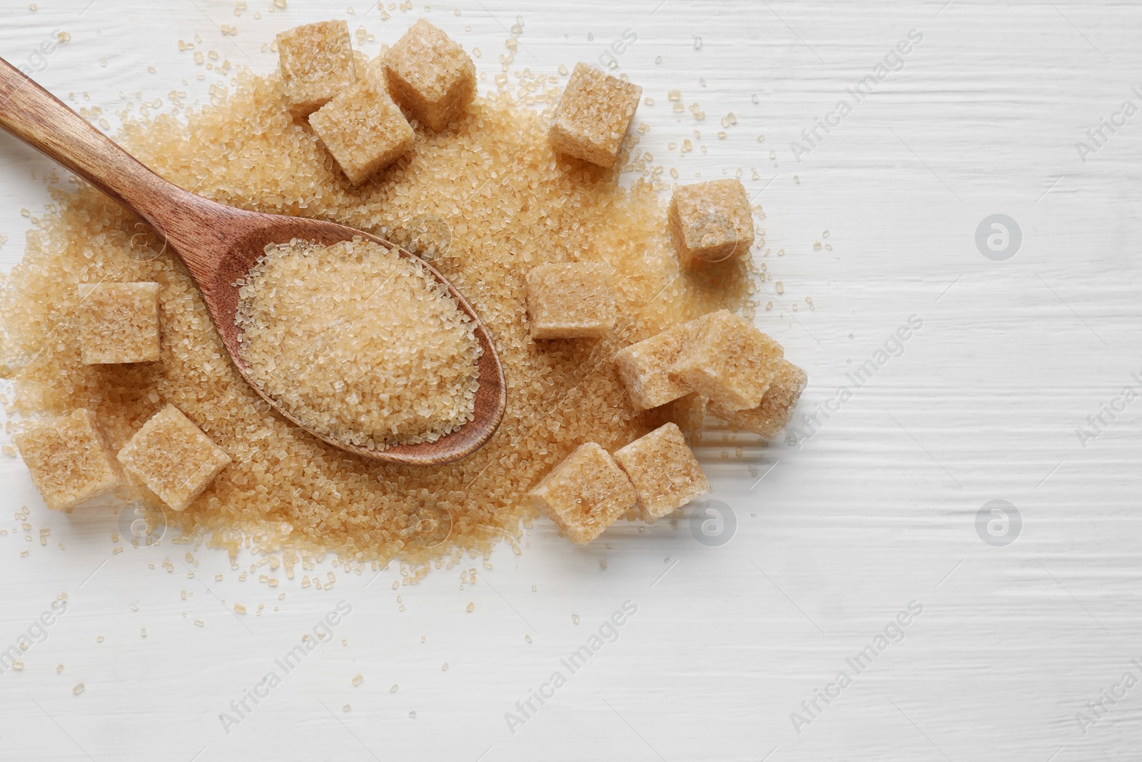 Photo of Different types of brown sugar on white wooden table, top view. Space for text