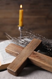 Wooden cross, Bible and willow branches on table, closeup