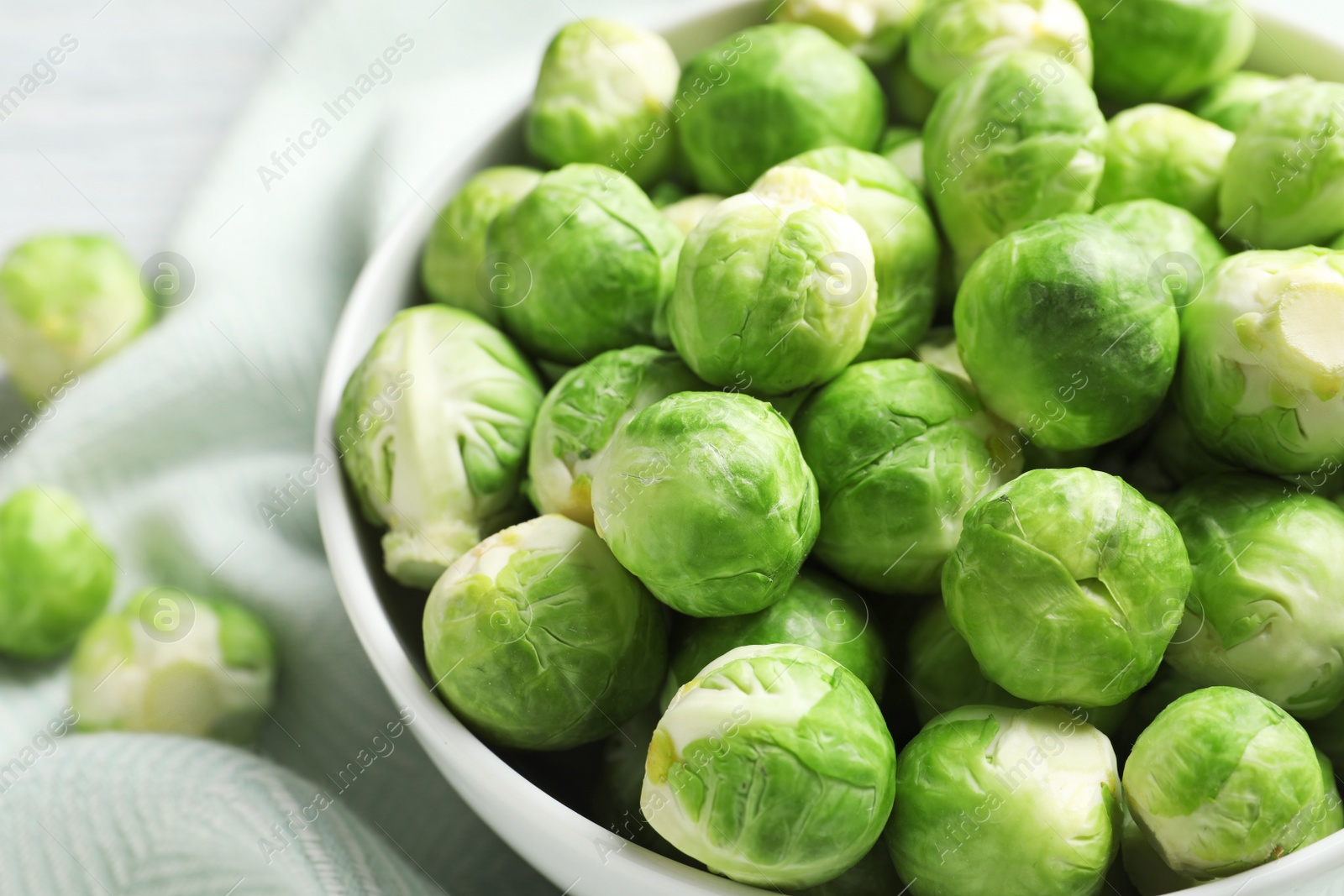 Photo of Bowl of fresh Brussels sprouts on fabric, closeup