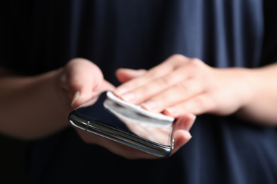 Photo of Woman cleaning smartphone with cotton pad, closeup