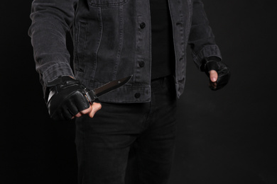 Photo of Man with knife on black background, closeup. Dangerous criminal