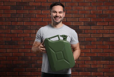 Photo of Man holding khaki metal canister against brick wall
