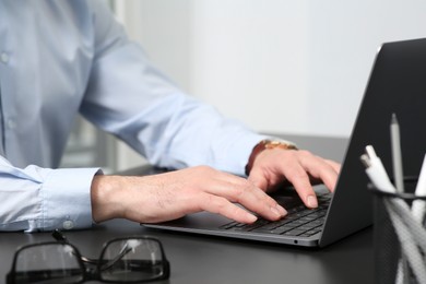 Photo of Man working on laptop at black desk in office, closeup