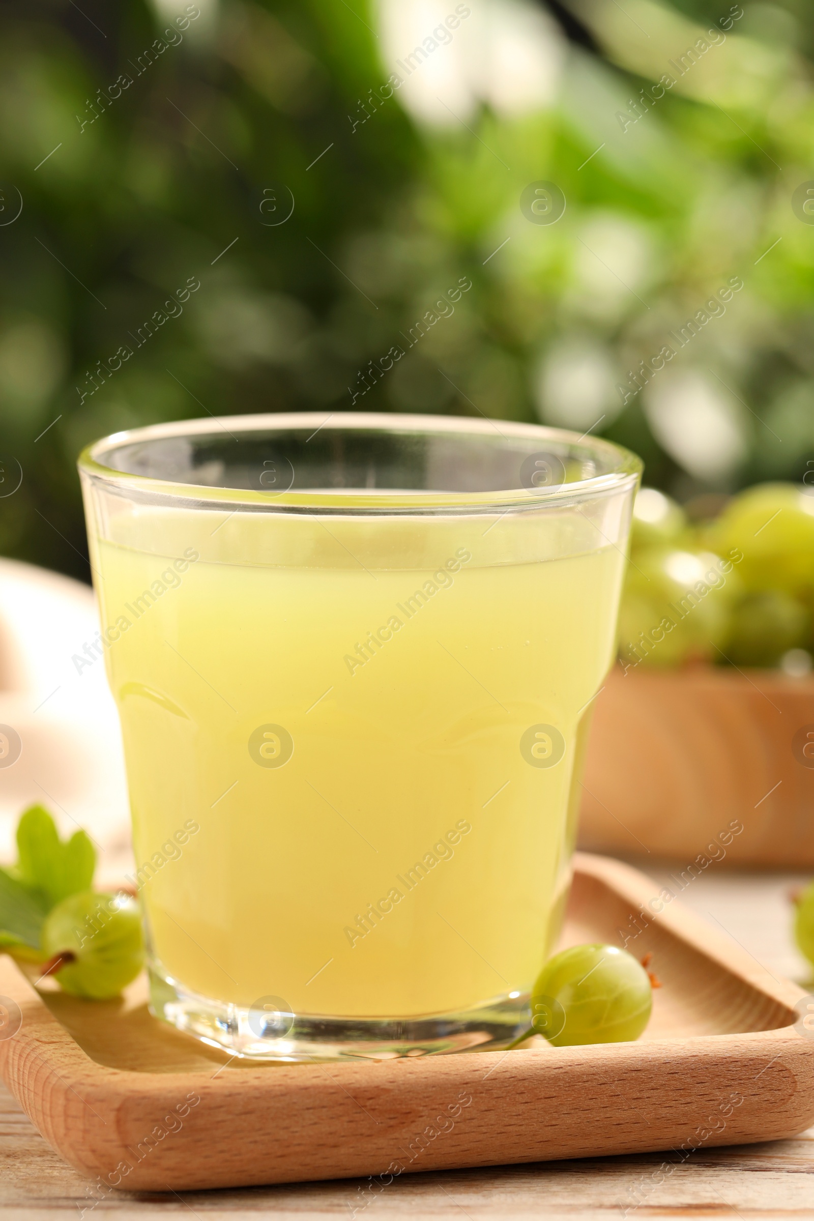 Photo of Tasty gooseberry juice and fresh berries on wooden table, closeup