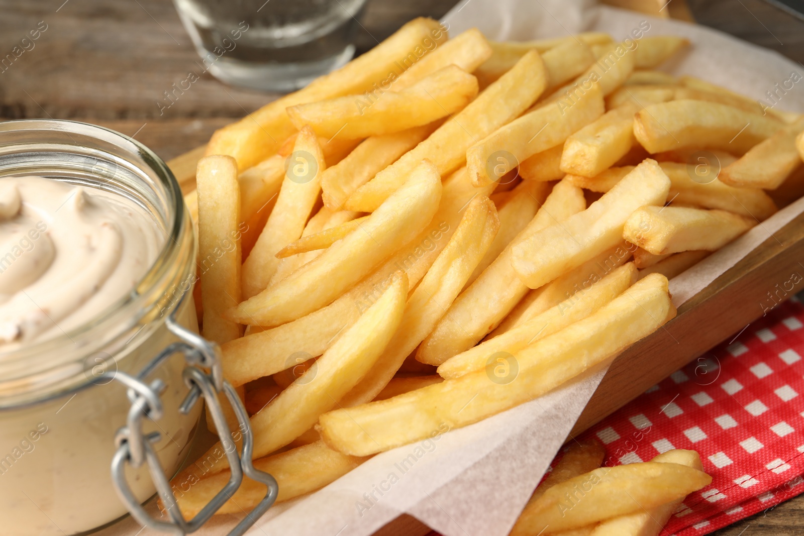 Photo of Delicious french fries served with sauce on wooden table, closeup