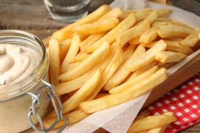 Delicious french fries served with sauce on wooden table, closeup