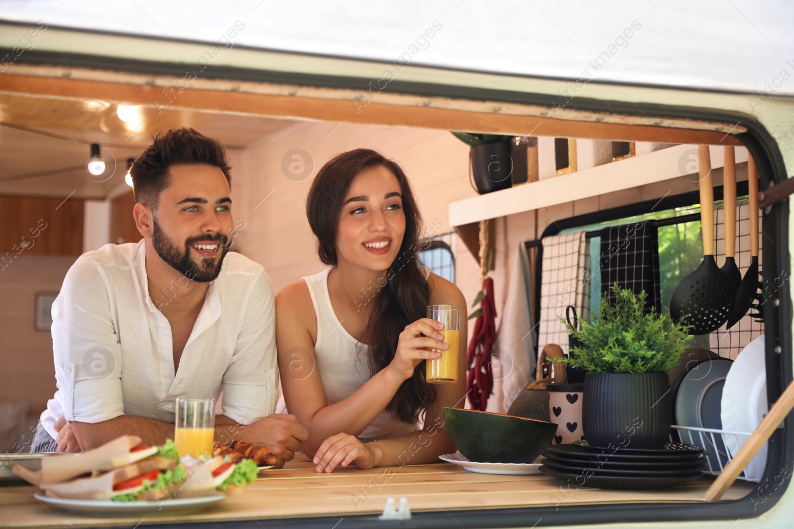 Photo of Happy young couple having breakfast in trailer. Camping vacation