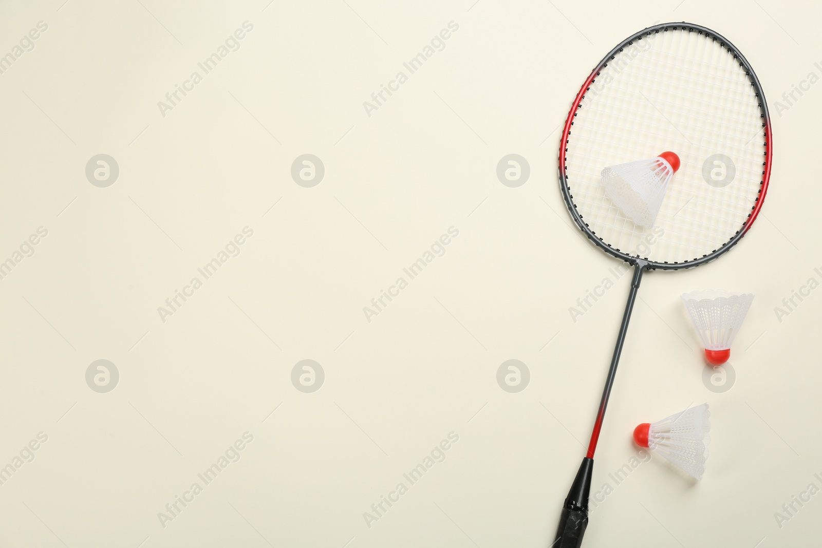 Photo of Racket and shuttlecocks on beige background, flat lay with space for text. Badminton equipment