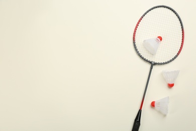 Racket and shuttlecocks on beige background, flat lay with space for text. Badminton equipment