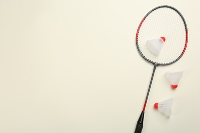 Photo of Racket and shuttlecocks on beige background, flat lay with space for text. Badminton equipment