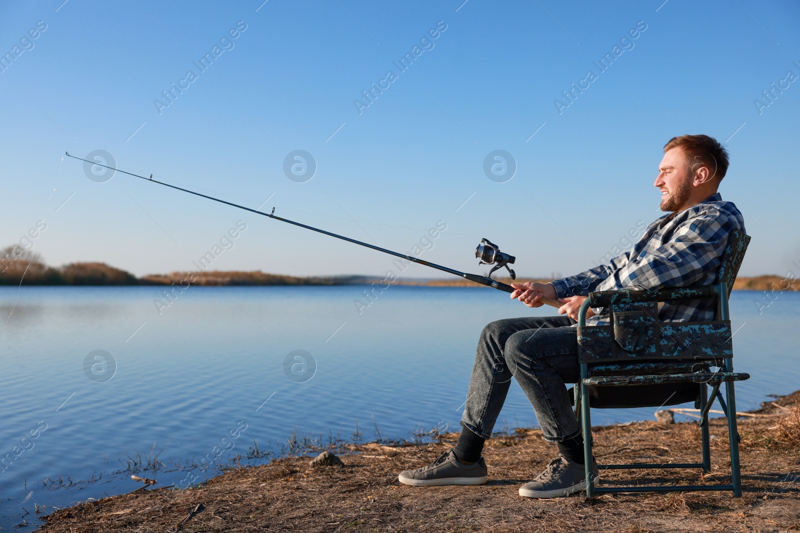 Photo of Fisherman with rod fishing at riverside. Recreational activity