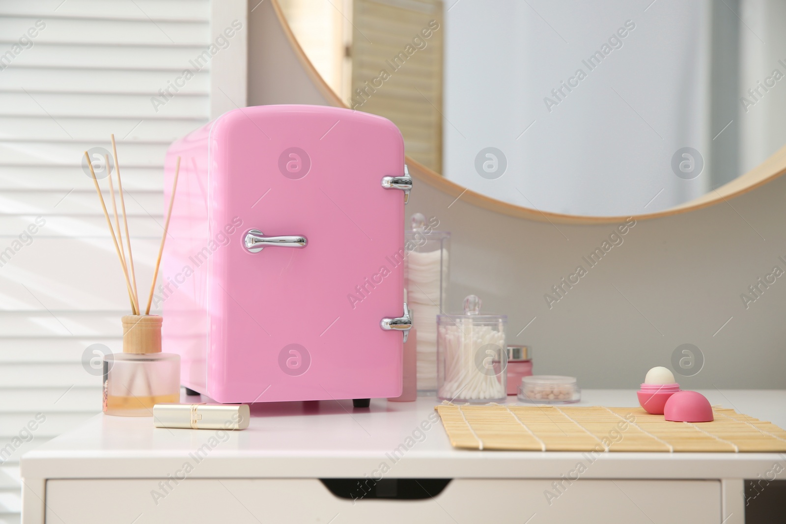 Photo of Cosmetics refrigerator and skin care products on white vanity table indoors