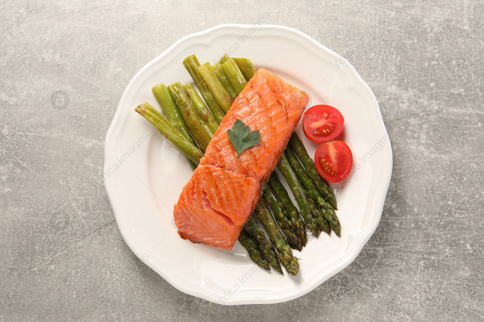 Photo of Tasty grilled salmon with tomatoes and asparagus on grey table, top view