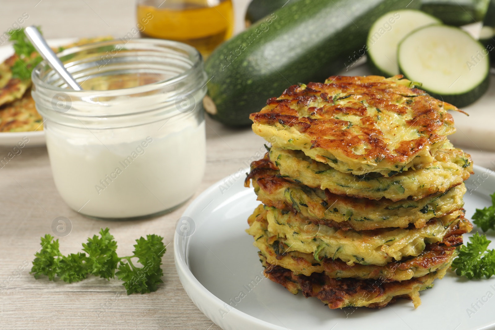 Photo of Delicious zucchini fritters served on white wooden table, closeup