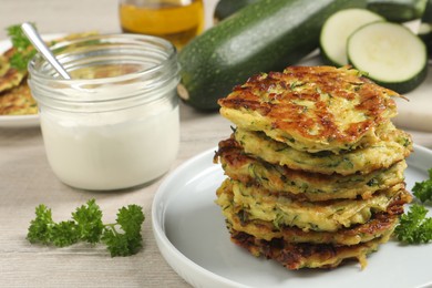 Photo of Delicious zucchini fritters served on white wooden table, closeup