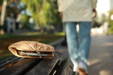 Photo of Woman lost her purse on wooden surface outdoors, selective focus