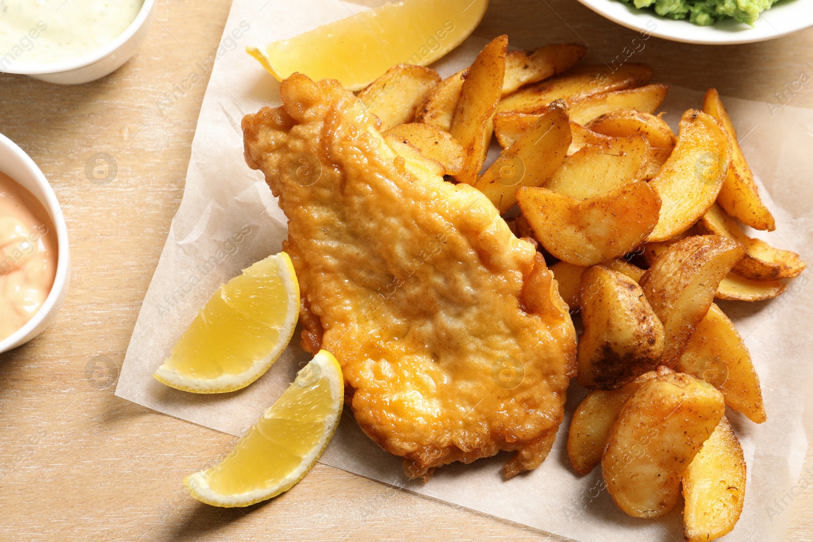 Photo of British traditional fish and potato chips on wooden background, closeup