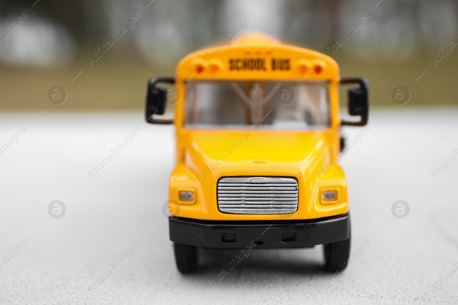 Photo of Yellow toy school bus against blurred background, closeup. Transport for students