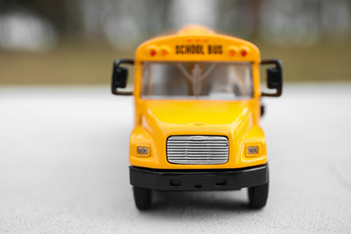 Photo of Yellow toy school bus against blurred background, closeup. Transport for students