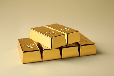 Photo of Many shiny gold bars on beige background