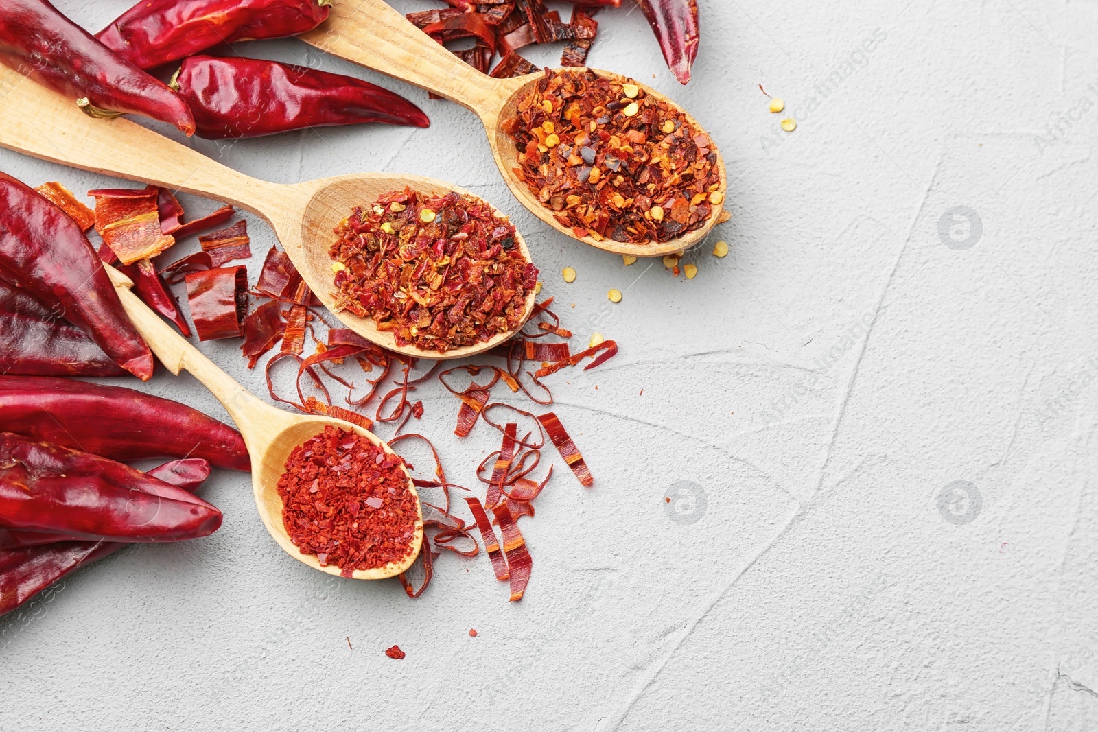 Photo of Composition with dry chili peppers and flakes on light background