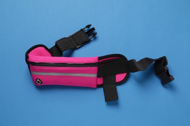 Photo of Stylish pink waist bag on light blue background