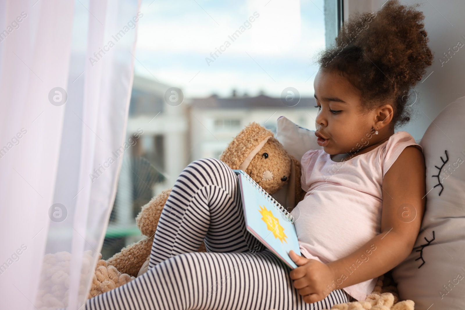 Photo of African American girl reading book at home