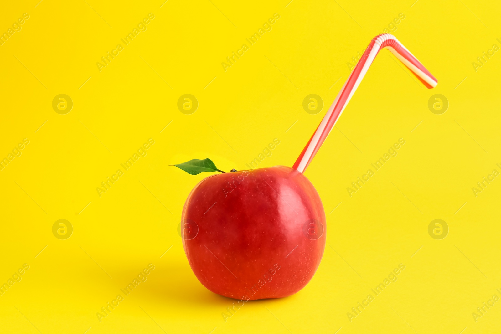 Photo of Fresh apple with straw on yellow background. Natural juice concept