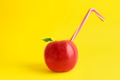 Fresh apple with straw on yellow background. Natural juice concept