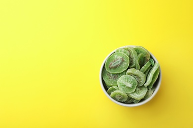Photo of Bowl of dried kiwi on color background, top view with space for text. Tasty and healthy fruit