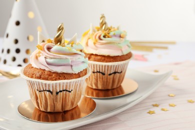 Photo of Plate with cute sweet unicorn cupcakes on white table, closeup. Space for text