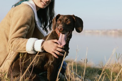 Woman with her German Shorthaired Pointer dog near river, closeup